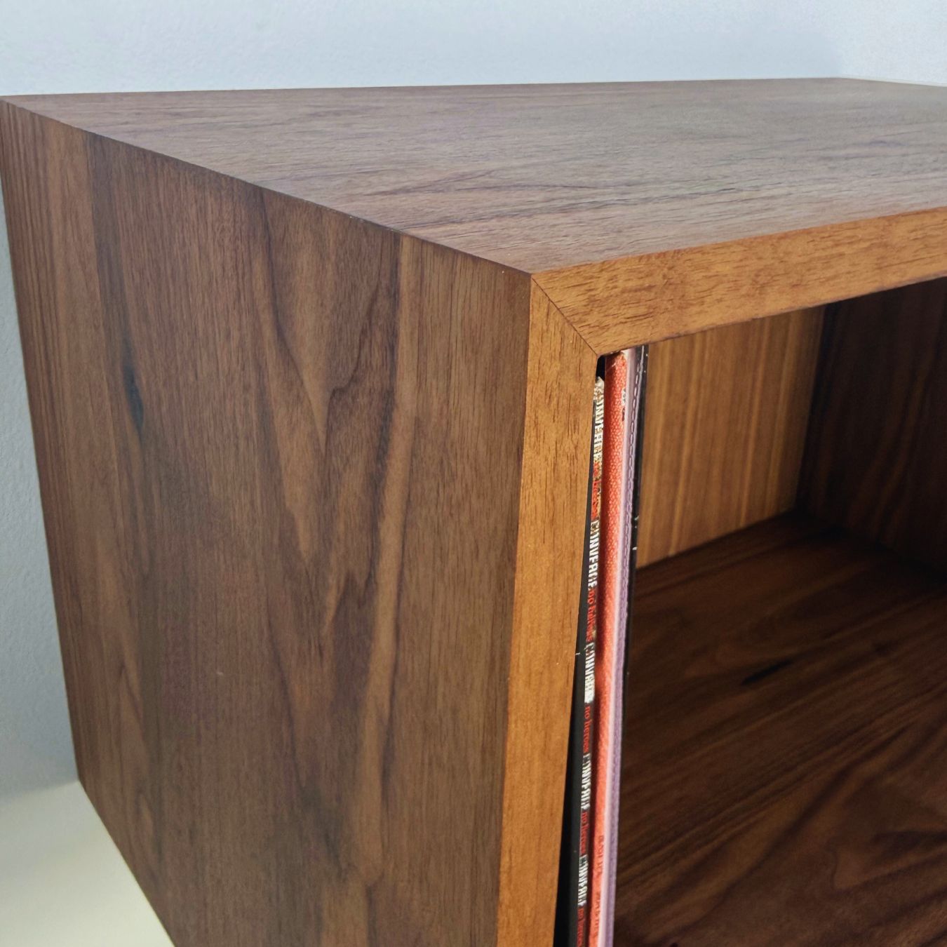Wooden shelf with vinyl records inside, against a plain background