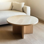 Handcrafted round white oak coffee table with a smooth minimalist design, placed in a modern living room with neutral tones and elegant decor.