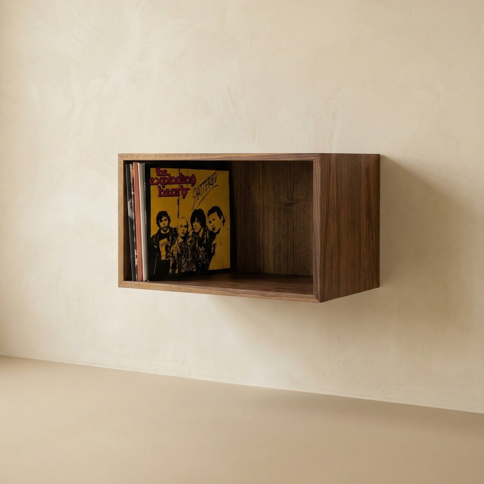 Wooden wall shelf with vinyl records against a beige wall